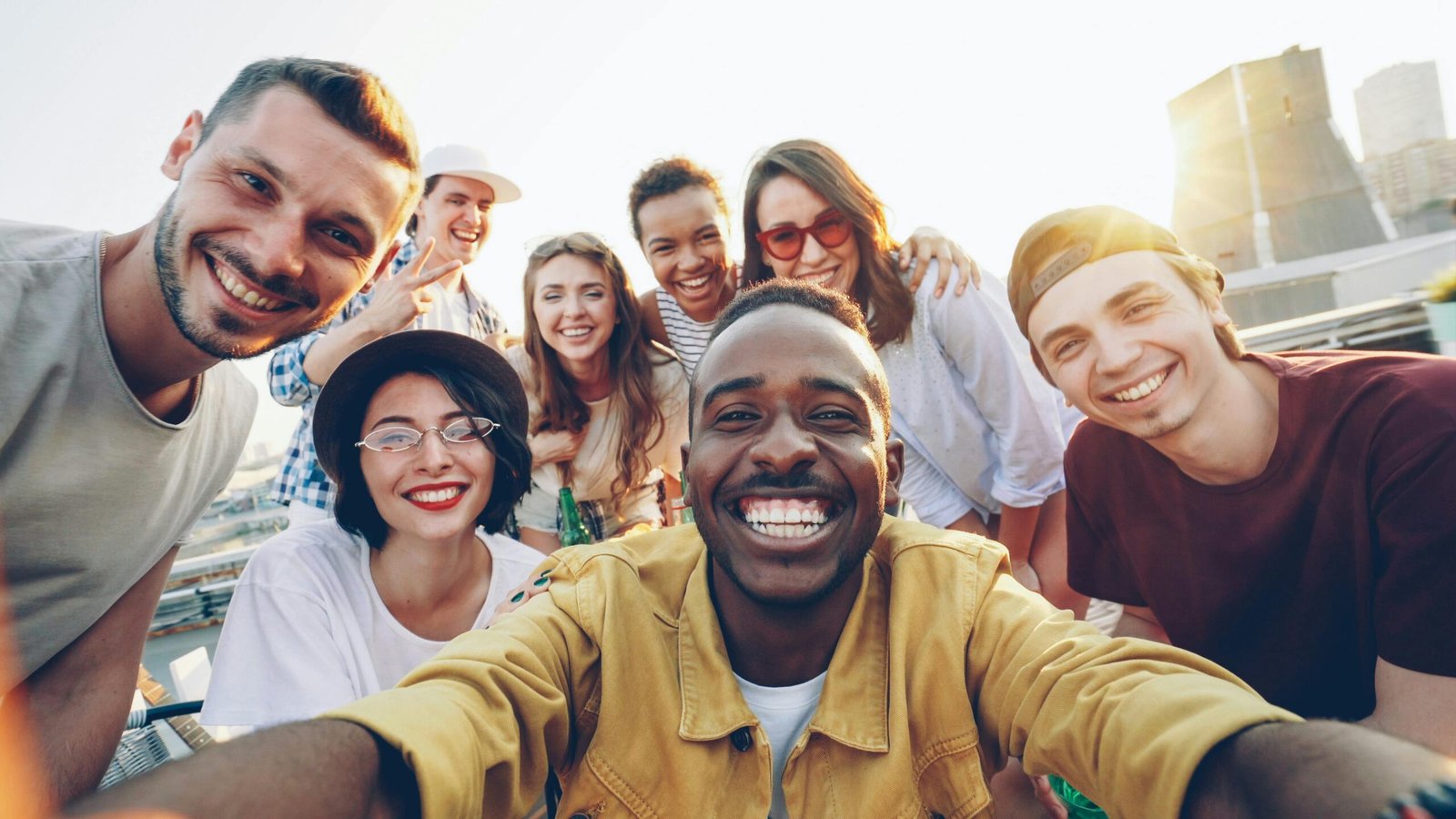 Diverse group of friends smiling and taking a selfie on a sunny day.
